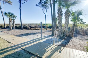 A wooden boardwalk leading to a sandy beach area with palm trees and a clear sky. - AMAZING views! Full DIRECT Oceanfront Villa! Totally renovated!  (Hilton Head Island)