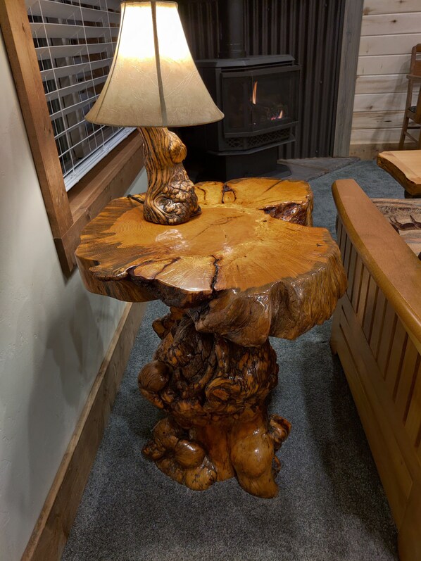 A wooden table with a unique design, a lamp, and a fireplace in the background.