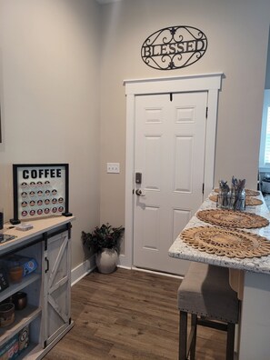 Cozinha com um letreiro na parede com tema de café, uma porta e bancada com jogos americanos.