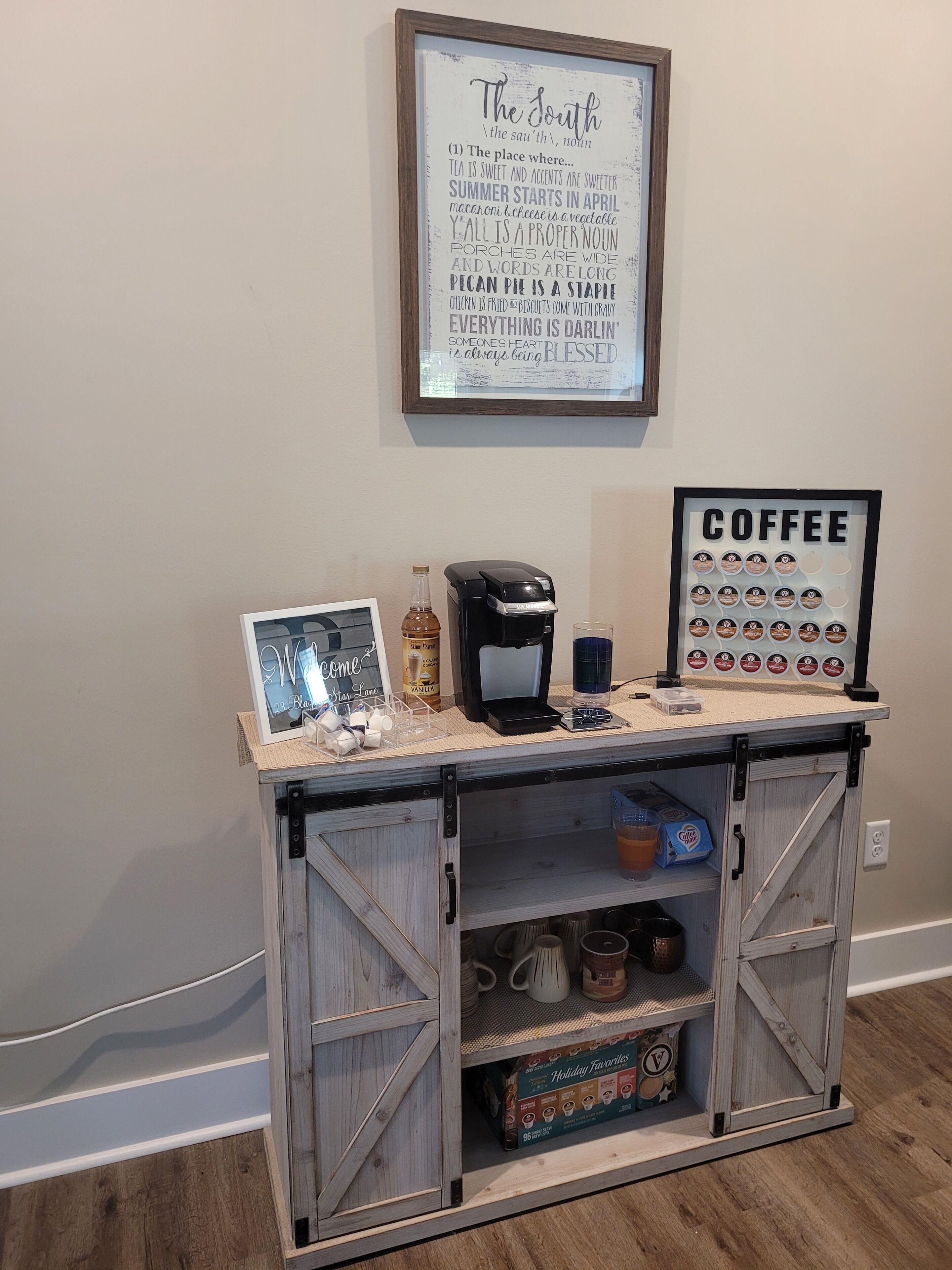 A coffee station with a sign, a coffee maker, and a mug.
