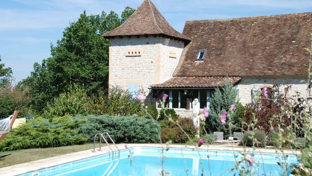 A stone tower with a conical roof, a swimming pool, and lush greenery. - Character house with swimming pool between Lot and Dordogne (Gourdon)