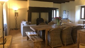 A cozy living room with a wooden table, wicker chairs, a bench, a fireplace, and a floor lamp. - Character house with swimming pool between Lot and Dordogne (Gourdon)
