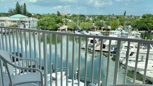 Ein Balkon mit weißen Korbmöbeln und Blick auf eine Marina mit Booten.