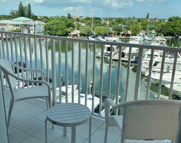 A balcony with white wicker furniture and a view of a marina with boats.