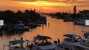 Eine Marina mit vertäuten Booten, ruhiges Gewässer und ein Sonnenuntergang im Hintergrund.