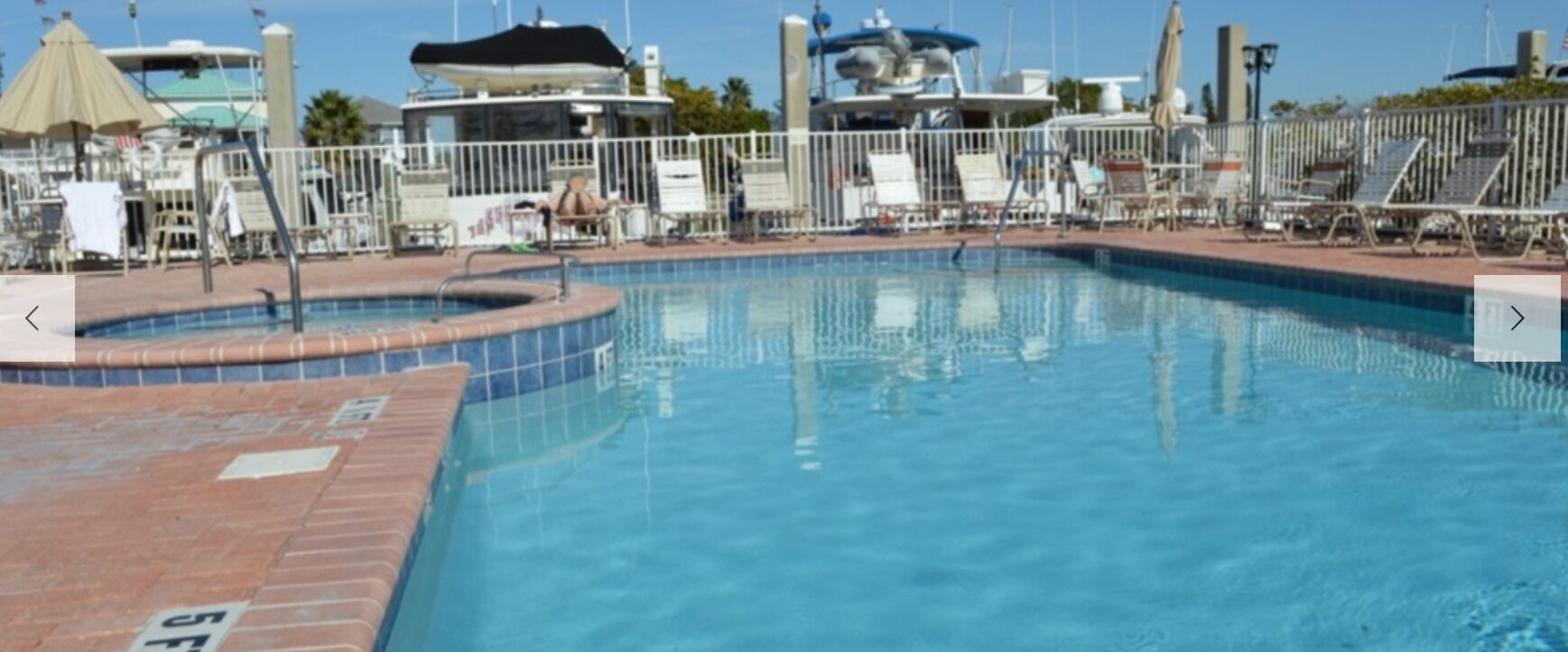 A swimming pool with a tiled edge, a lifeguard stand, and lounge chairs.