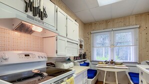 Eine Küche mit weißen Schränken, einem Herd, einem Toaster und einem Fenster mit Jalousien.