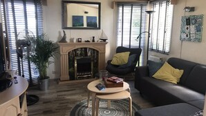 Una sala de estar acogedora con chimenea, un sof á, un sillón y una mesita.