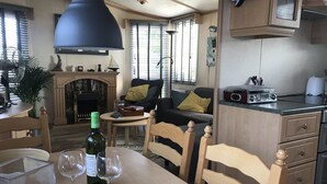 Una sala de estar acogedora con chimenea, un comedor con mesa lista para dos personas y una cocina con armarios de madera y un tostador.