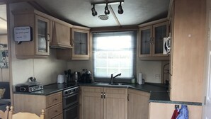Una cocina compacta con armarios de madera, estufa y lavabo.