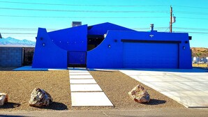 A blue building with a garage door, a paved walkway, and a mountain in the background. - The Dorado Blue ~Spectacular views (Bullhead City)