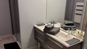 Une salle de bain moderne avec un double vasque, un grand miroir avec éclairage intégré et un porte-serviettes.