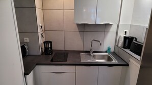 Une petite cuisine équipée d’un évier, d’une machine à café et d’un grille-pain posés sur le plan de travail.