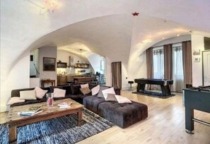 Relax in this spacious living area with a high arched ceiling, featuring a sofa set, coffee table, and pool table.