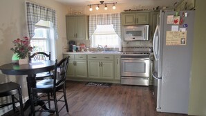 A kitchen with green cabinets, a stainless steel refrigerator, and a dining area with a table and chairs. - ❤️ Romantic Couples Retreat in the country❤️Farm Stay  (Ephrata)