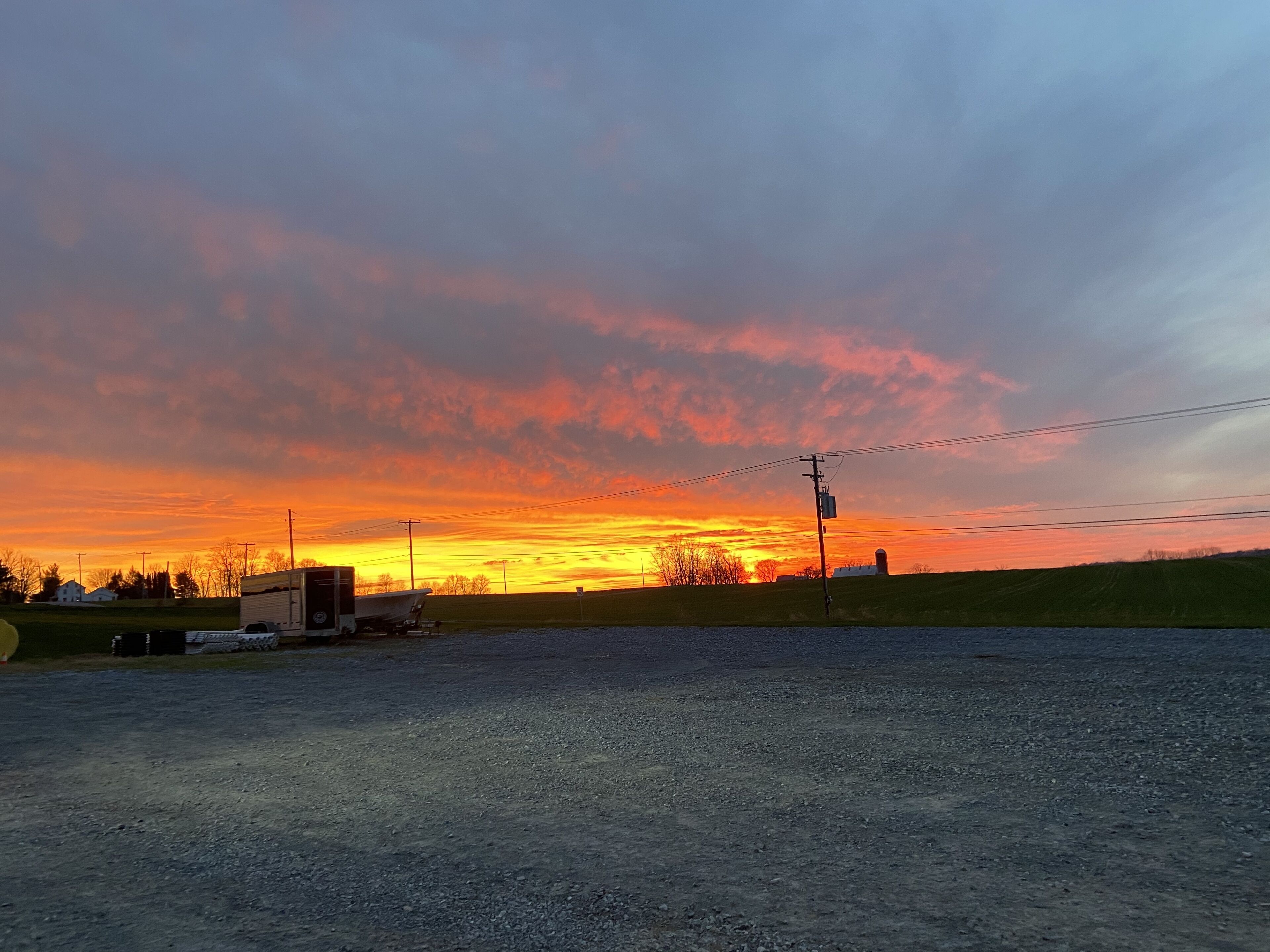 Landskab med solnedgang, åbne marker og en campingvogn.