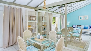 A dining area with a glass table and wicker chairs, a white wicker sofa, and a blue wall with starfish decorations. - Beachfront Resort Condo, Walk to Atlantis (Paradise Island)