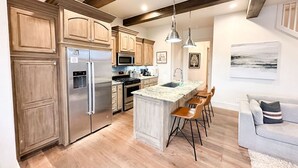 A modern kitchen with wooden cabinets, stainless steel appliances, and a central island with bar stools. - 15% off gorgeous cottage, hot tub, pool, fishing ponds, streams, waterfalls! (Vinita)