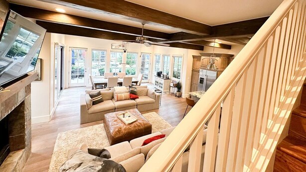 A spacious living area with a fireplace, large windows, and a kitchen in the background. - 15% off gorgeous cottage, hot tub, pool, fishing ponds, streams, waterfalls! (Vinita)