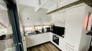 A compact kitchen with white cabinets, a black countertop, and a wooden floor.