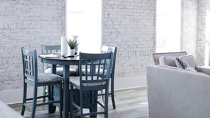 A dining area with a round table, blue chairs, and a white brick wall. - Charming Loft (Nashville)