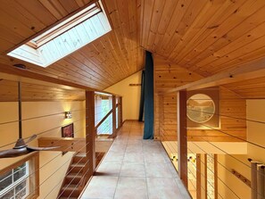 Un interior de madera con una escalera, tragaluces y vistas a través de una ventana.