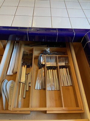 Un cajón con cubiertos ordenados, incluyendo tenedores, cuchillos y cucharas.