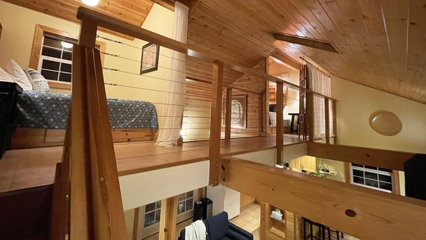 Una cabaña de madera de varios niveles con un dormitorio en altillo, un comedor y una cocina.