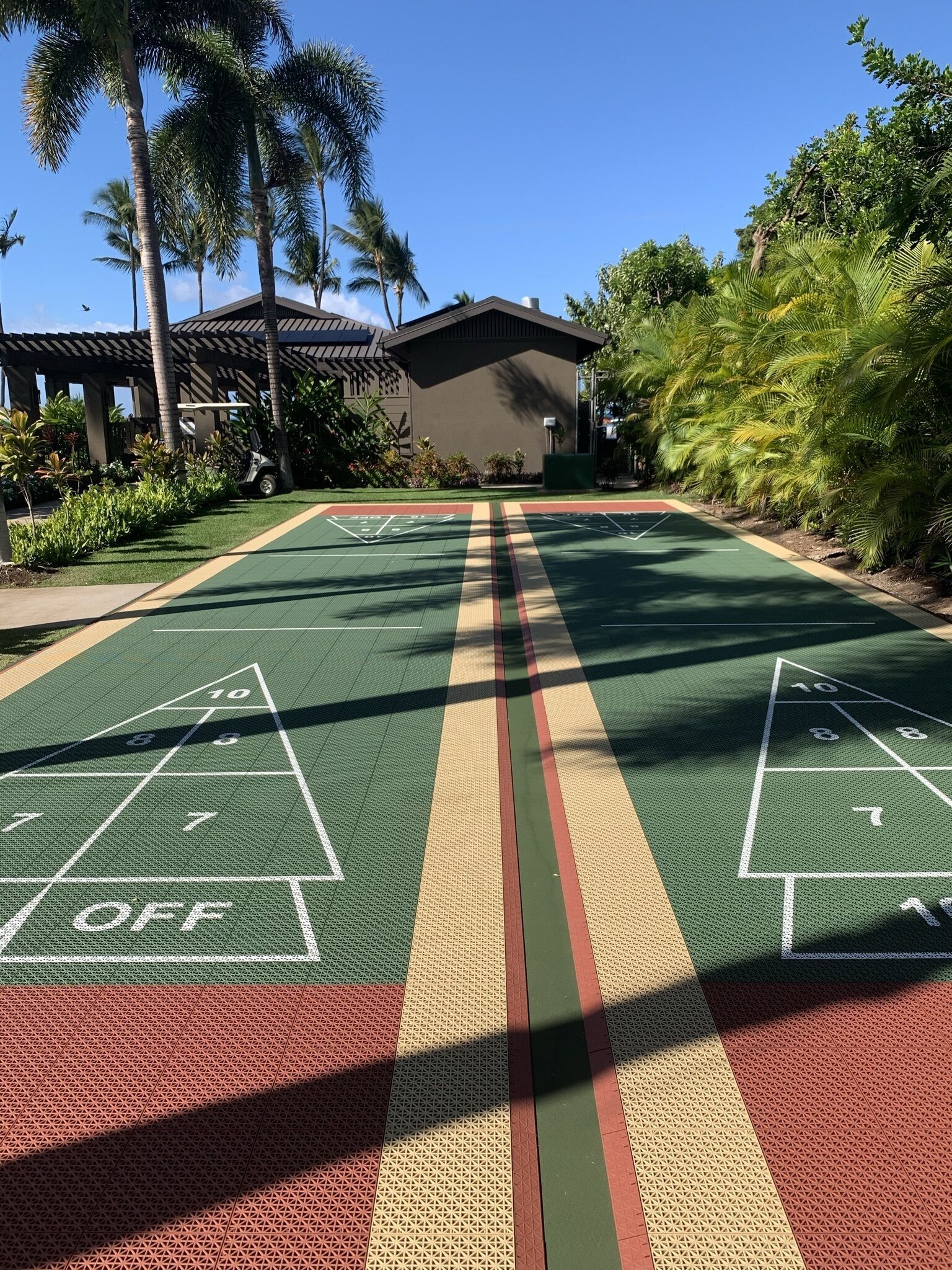 Una cancha de shuffleboard con un edificio al fondo.