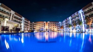 Un hôtel doté d’une grande piscine bien éclairée et d’une architecture moderne.