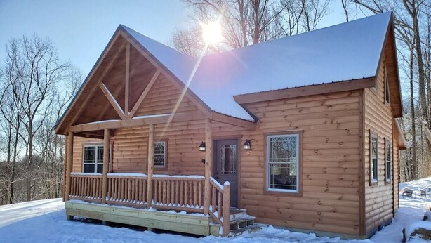 Une cabane en bois avec un porche, un garage et une petite terrasse.