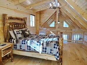 A rustic wooden bedroom with a bed, a nightstand, and a chandelier. - Ace of Hearts. Secluded Hocking Hills cabin! (Rockbridge)