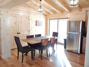 A wooden interior with a dining table, chairs, a refrigerator, and a window. - Ace of Hearts. Secluded Hocking Hills cabin! (Rockbridge)