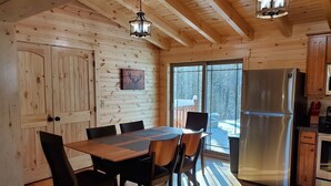 Un intérieur en bois comprenant une table à manger, des chaises, un réfrigérateur et un coin cuisine.