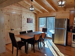 Un intérieur en bois comprenant une table à manger, des chaises, un réfrigérateur et un coin cuisine.