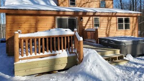 Une cabane en bois dotée d’un porche couvert et d’un bain à remous.