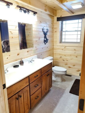A wooden cabin bathroom with a wooden vanity, a sink, a toilet, and a window. - Ace of Hearts. Secluded Hocking Hills cabin! (Rockbridge)