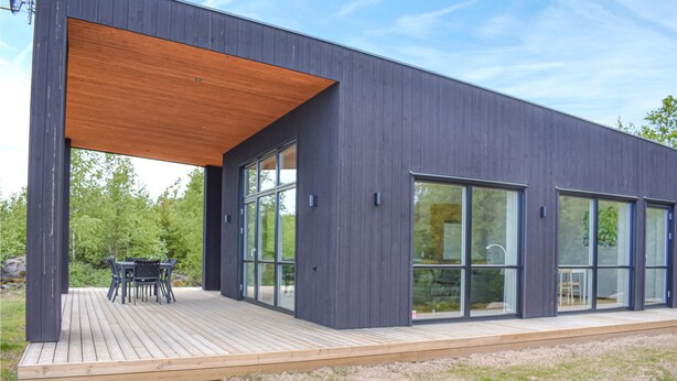 Een modern gebouw met grote glazen deuren en een houten terras.