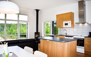 Enjoy cooking in this kitchen with a central island, stove, and microwave above the sink, offering views of the surrounding forest.