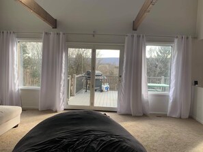 Une chambre avec un grand lit, une porte-fenêtre coulissante donnant sur un balcon équipé d’un barbecue et d’une table.