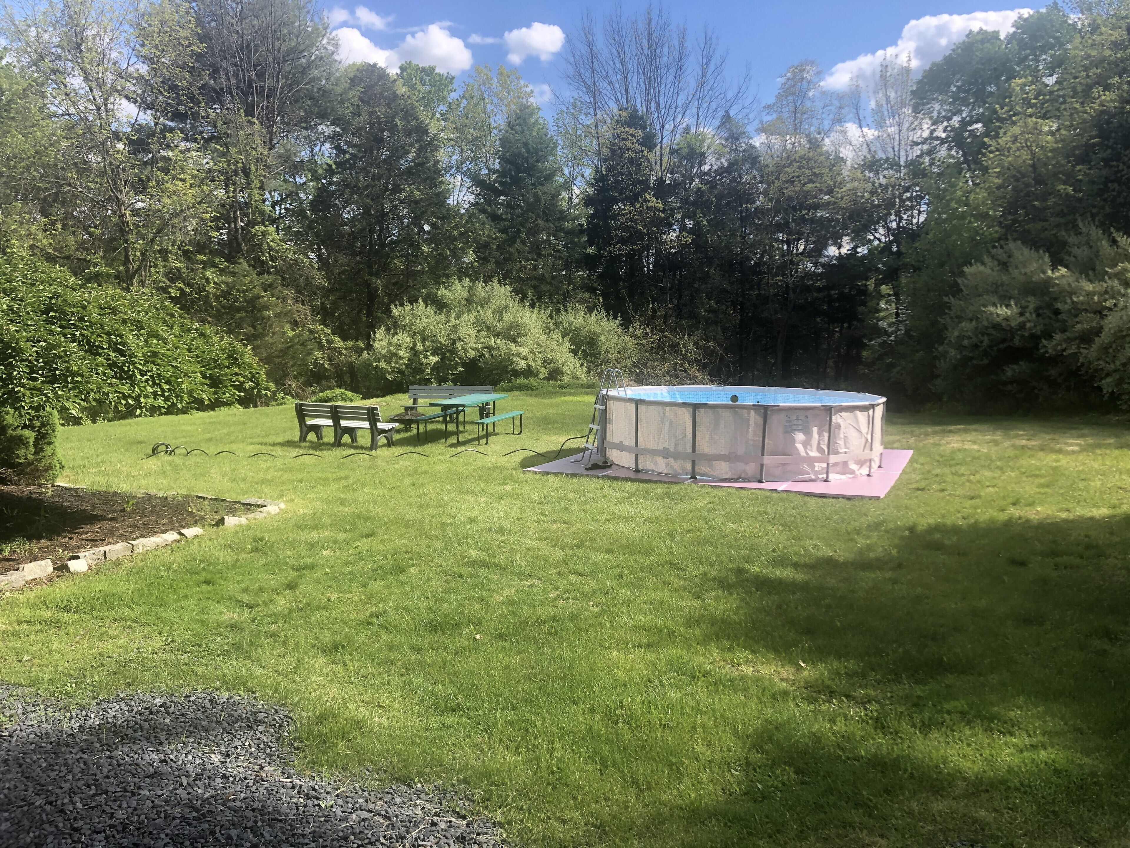 A backyard with a swimming pool, a picnic table, and a bench.