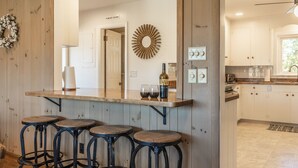 A kitchen with wooden cabinets, a bar area with stools, and a sign indicating a powder room. - Amazing Views - Heated Pool - Hot Tub - Game Room - Enjoy! (Landrum)