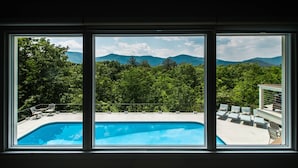 A swimming pool with lounge chairs and a view of mountains through large windows. - Amazing Views - Heated Pool - Hot Tub - Game Room - Enjoy! (Landrum)