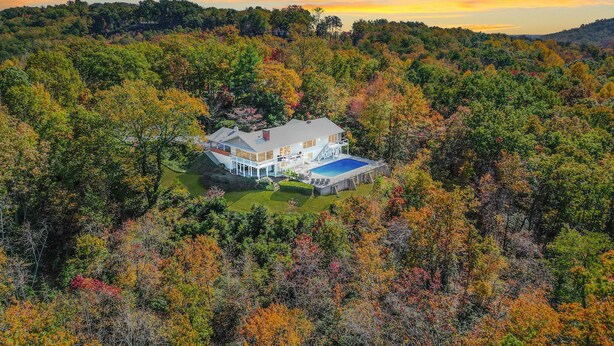A large house surrounded by autumn foliage, with a visible swimming pool and a covered outdoor area. - Amazing Views - Heated Pool - Hot Tub - Game Room - Enjoy! (Landrum)
