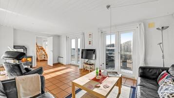 Un salon spacieux doté d’une cheminée, d’un téléviseur et offrant une vue sur l’extérieur.