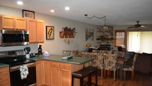 A kitchen with wooden cabinets, a microwave, and a stove. There is a dining area with a table and chairs.