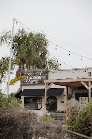 A building with a sign reading 'Seaside Surf Cafe' and a sign that says 'Trust The Bum.'