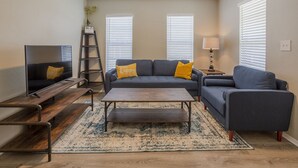A living room with a sofa, coffee table, TV, and a ladder. - Centro Ybor Duplex! Walk to 7th Ave! Unit E12th-B (Tampa)