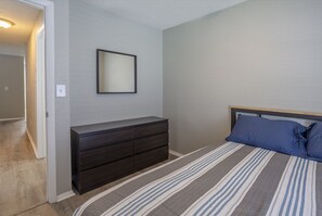 Un dormitorio con cama, cómoda y espejo en la pared.