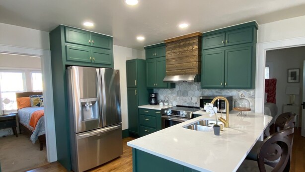 Una cocina moderna con armarios color turquesa, electrodomésticos de acero inoxidable y una isla central.